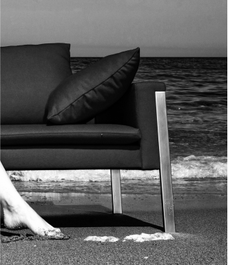 Modelo elegante posando com um sofá exclusivo na praia